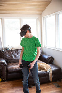 Teen boy playing with vr system with family dog behind him on couch