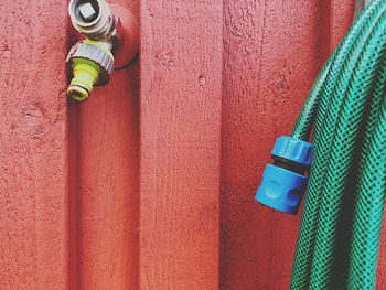 Yellow and blue water tap on red wooden wall 