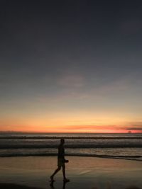 Full length of man walking on shore at beach during sunset