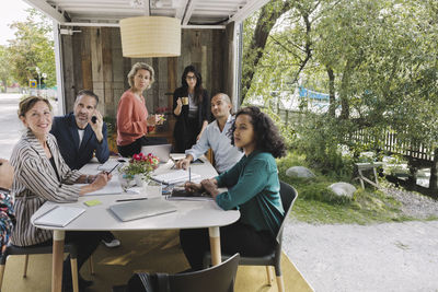 Business people looking at colleague giving presentation in portable office truck