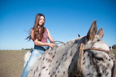 Young woman with horse in the background