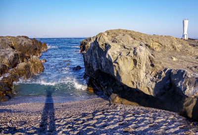 Rocks on beach against clear blue sky