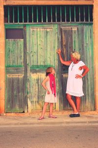 Girl looking at grandmother while standing on footpath