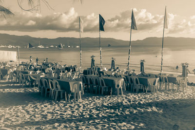 Chairs and tables on beach against sky