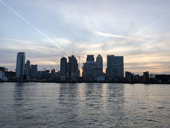 Scenic view of river by buildings against sky