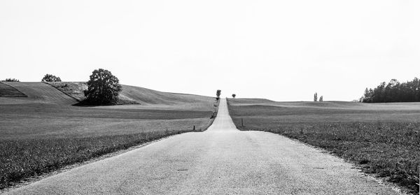 Empty road on field against clear sky