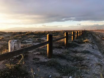 View of wooden fence by sea against sky