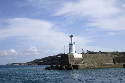 Lighthouse by sea against sky