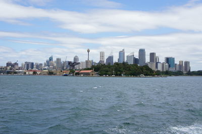 City at waterfront against cloudy sky