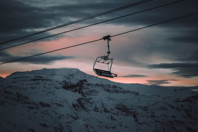 Overhead cable car on snowcapped mountains against sky during sunset