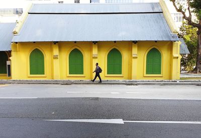 Side view of man walking on road against buildings