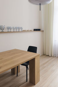 Interior of the minimalist dining room with a wooden table and glass glasses on a shelf