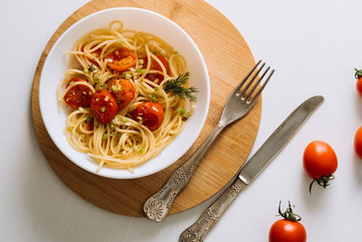 Flat lay portion of spaghetti pasta with cherry tomatoes sprinkled with spices in a plate