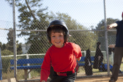 Young boy in baseball helmet with big smile on the tball field