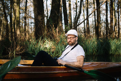 Man sitting in canoe on lake at forest