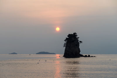 Rock formations amidst sea against sky during sunset