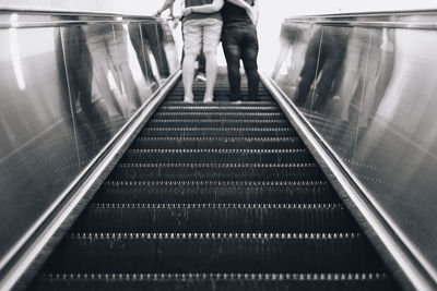 Rear view of people standing on escalator at railroad station