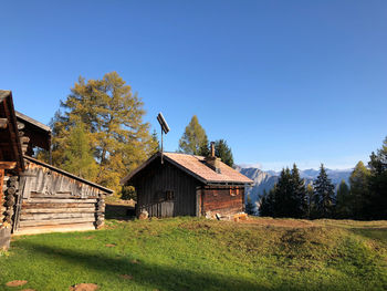 Houses and trees on field against clear blue sky