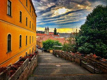 Walkway amidst buildings in city against sky