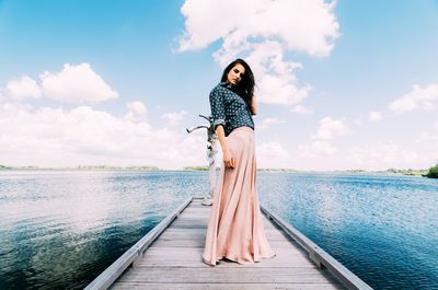 Woman standing on pier over sea against sky