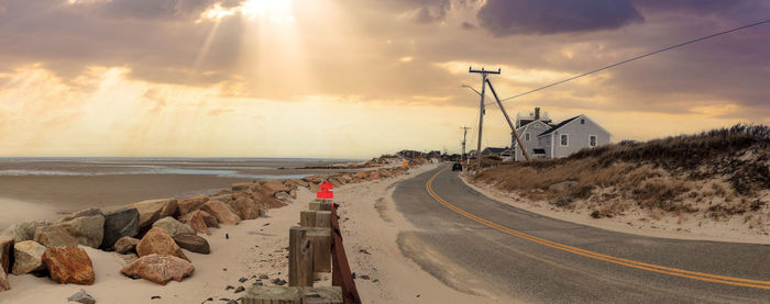 Sunlight through the storm clouds over roadway along chapin beach in cape cod, massachusetts.