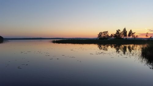 Scenic view of lake against clear sky during sunset