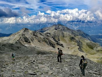 People hiking on mountain against landscape and sky