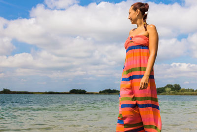 Woman standing by sea against sky