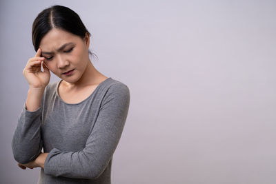 Young woman looking away while standing against wall