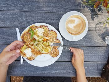 Cropped image of hand holding coffee cup on table