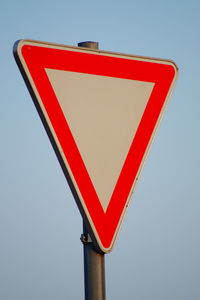 Low angle view of road sign against clear sky