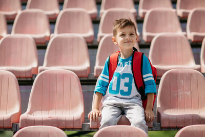 Boy sitting on chair at stadium