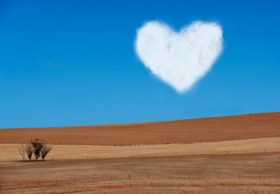 Heart shape on desert against blue sky
