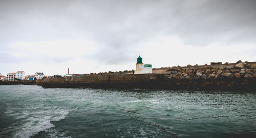 Lighthouse by sea against sky