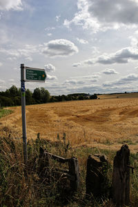 Information sign on field against sky