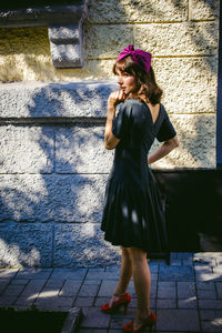 Beautiful young woman in black dress standing by building