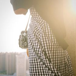 Close-up of hand holding camera against the sky