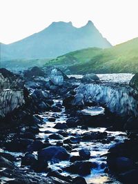 Scenic view of river by mountains against clear sky