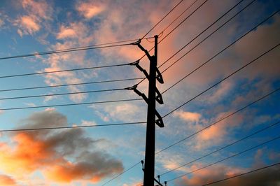 Low angle view of electricity pylon against cloudy sky