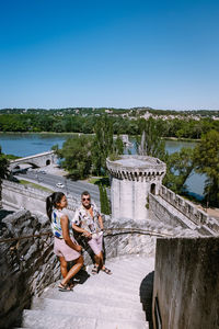 People sitting on shore against clear sky