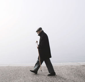 Side view of an old man standing  against sky