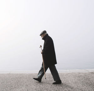 Side view of man standing on snow against sky