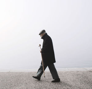 Side view of man standing on snow against sky