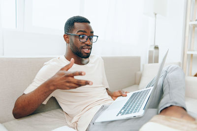 Portrait of young man using laptop at home