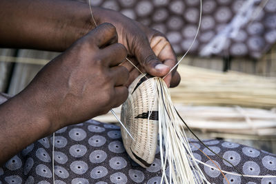 Cropped hands of worker making wicker basket in workshop