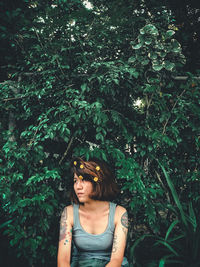 Young woman looking down while standing against plants