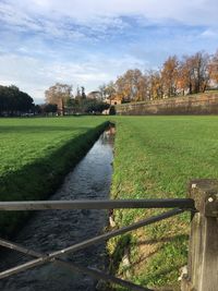 Canal amidst field against sky