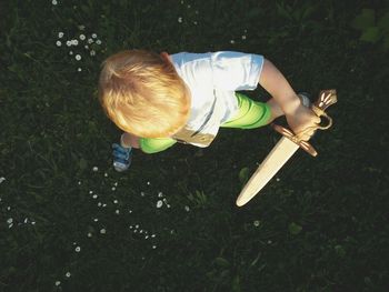 High angle view of playful boy with artificial sword on field