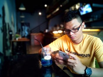 Man using mobile phone while sitting at table in cafe