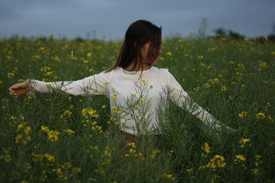 Woman with arms outstretched standing amidst plants